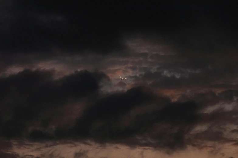 a plane flying into the night sky next to clouds