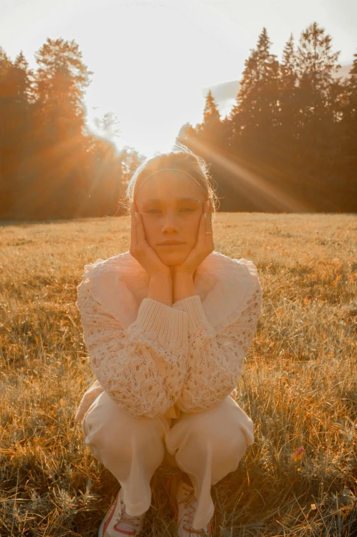  sitting down in grassy field with trees behind her