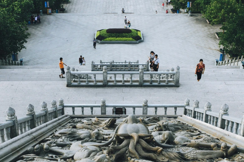 two people walking towards a long building filled with statues