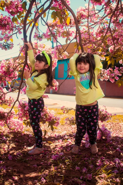 two girls wearing yellow and black outfits with flowers growing on the trees
