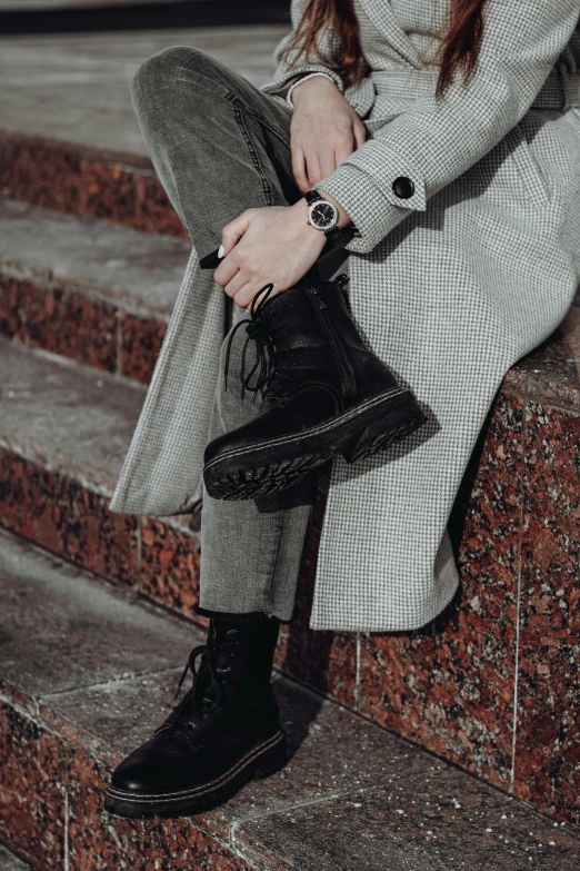 a woman wearing gray jacket and black boots on steps