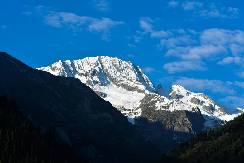 some snow mountains covered in trees and clouds