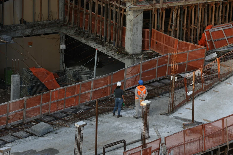 two construction workers standing near steel bars