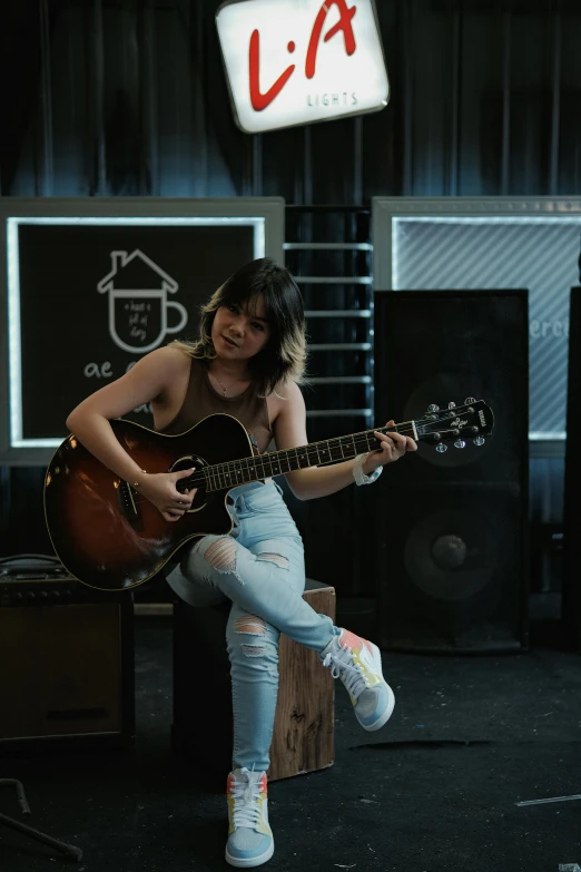 a girl playing an acoustic guitar while posing for a picture