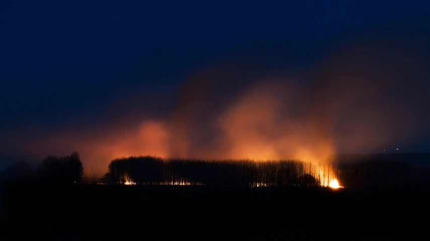 many fire raging out of a large, dark field