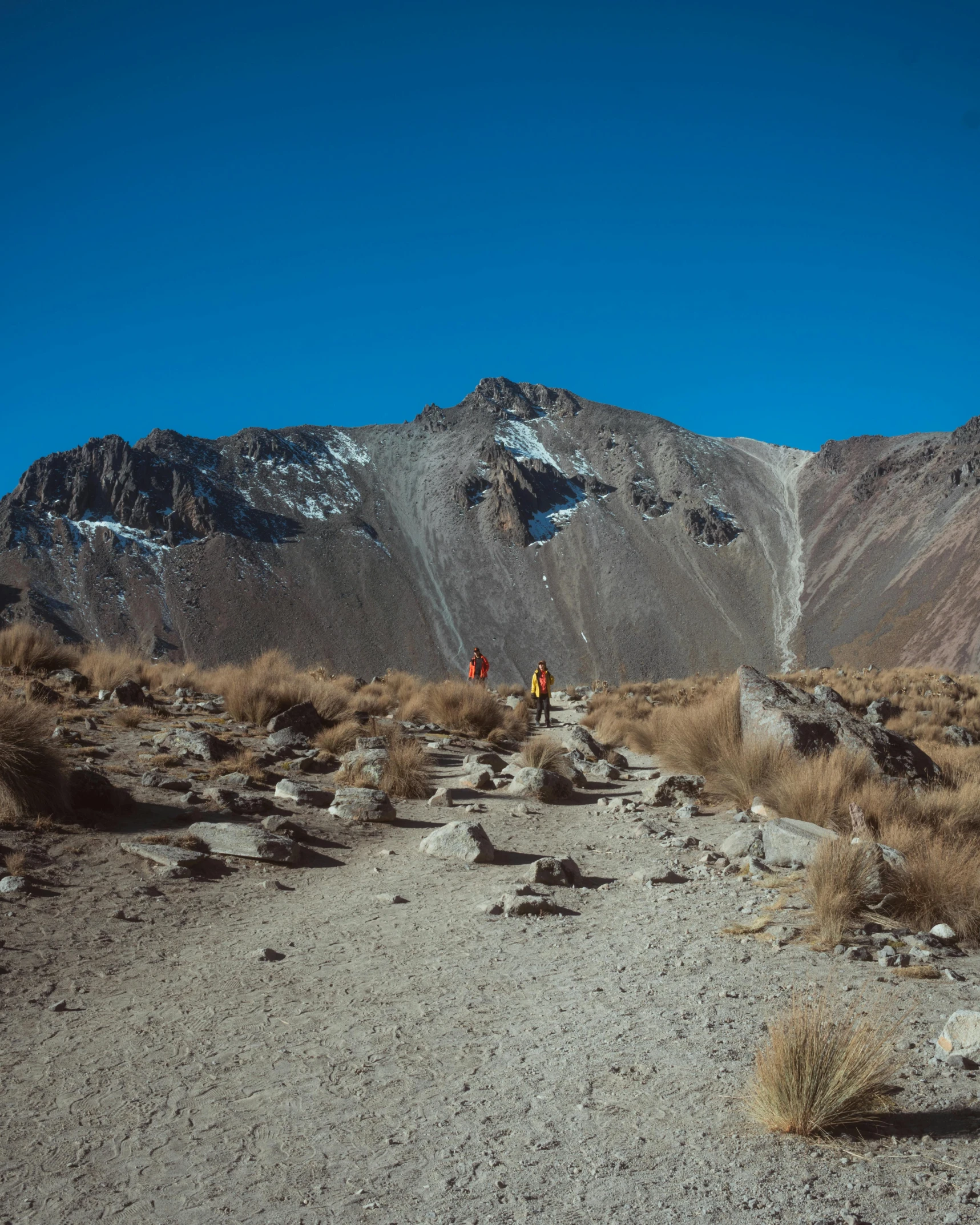 two hikers on path in alpine desert