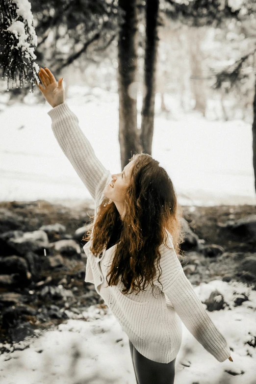 woman with snow on her face holds up a small fir tree