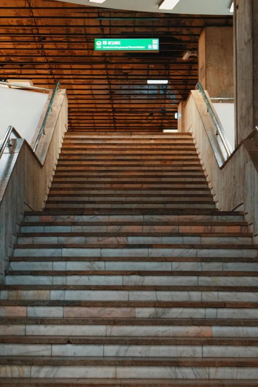 a stairwell with stairs and green sign above the stairs