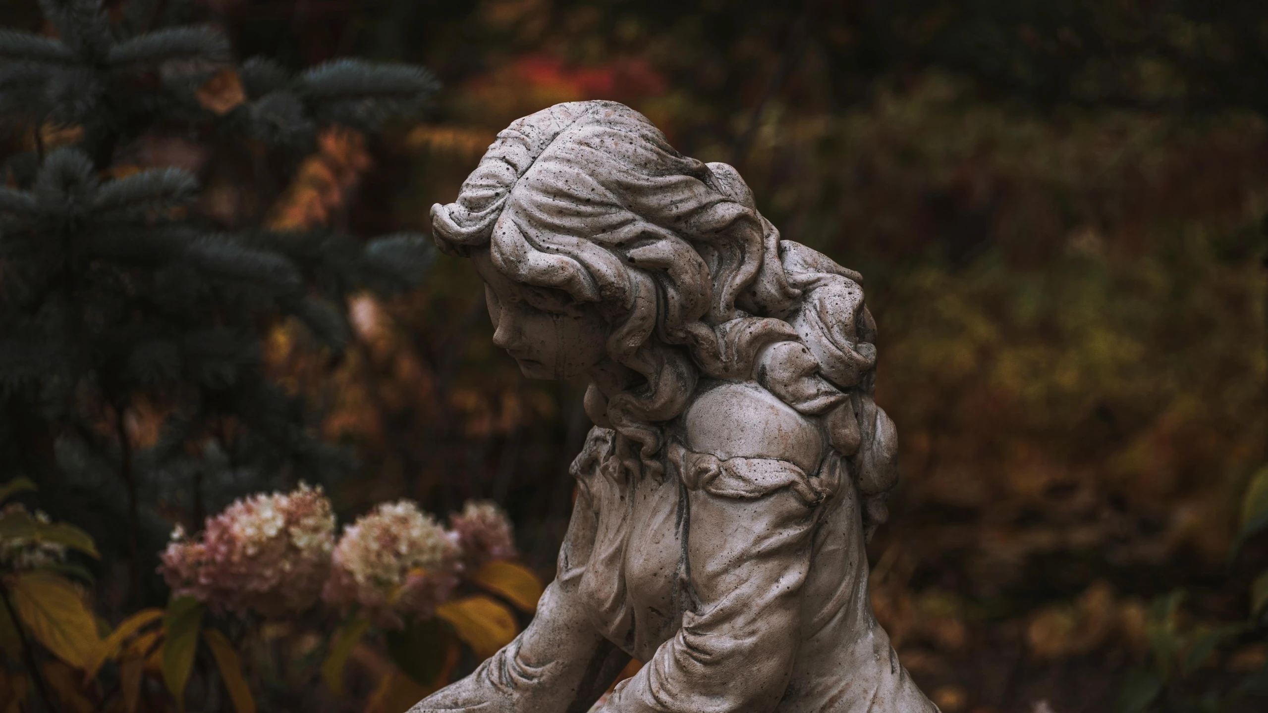 a stone sculpture with flowers behind it