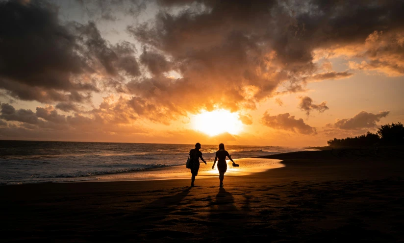 a couple is walking on a beach under a cloudy sky