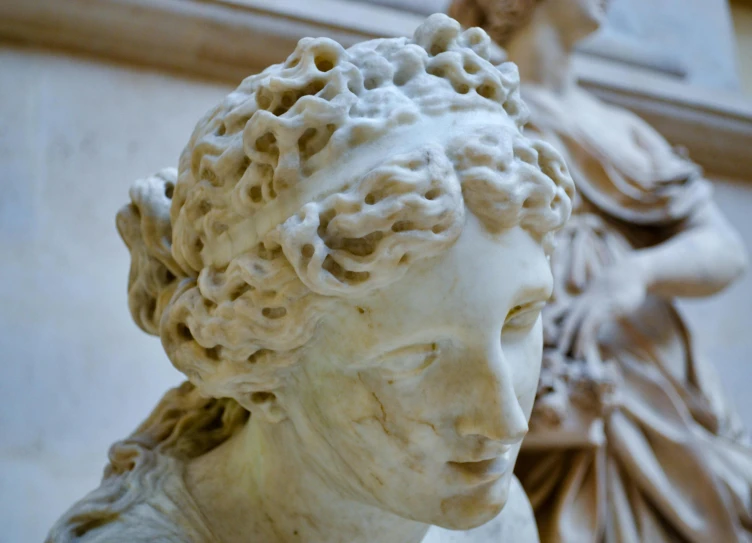 a white marble bust is standing in front of a white wall