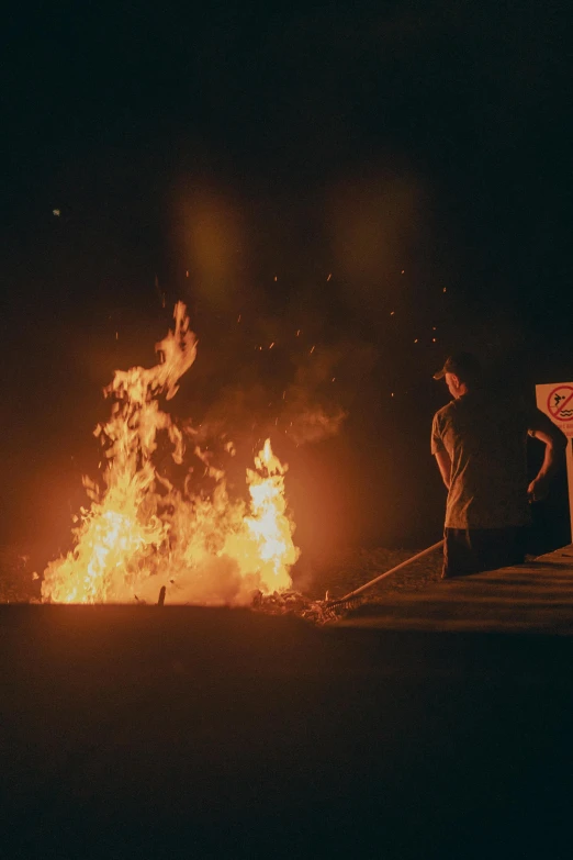 a man standing in front of a bonfire