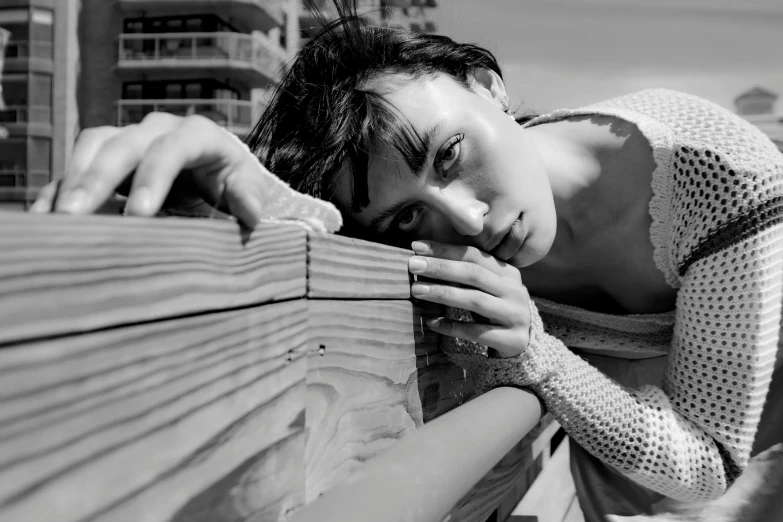 a woman leaning on the wall looking down and touching her hand