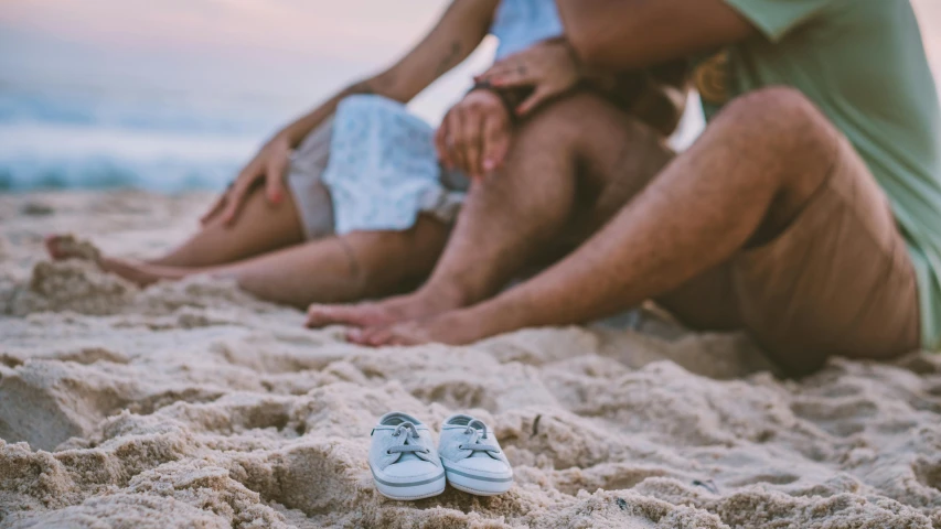 some people are sitting down on the beach