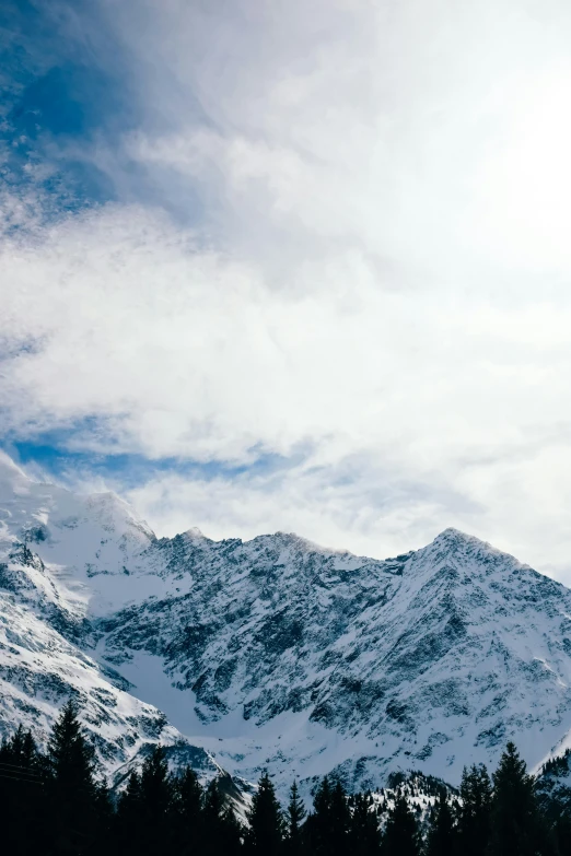 the snow capped mountains are silhouetted against the cloudy sky