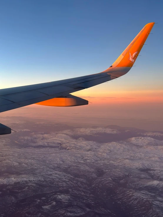 the wing of an airplane flying above some mountains