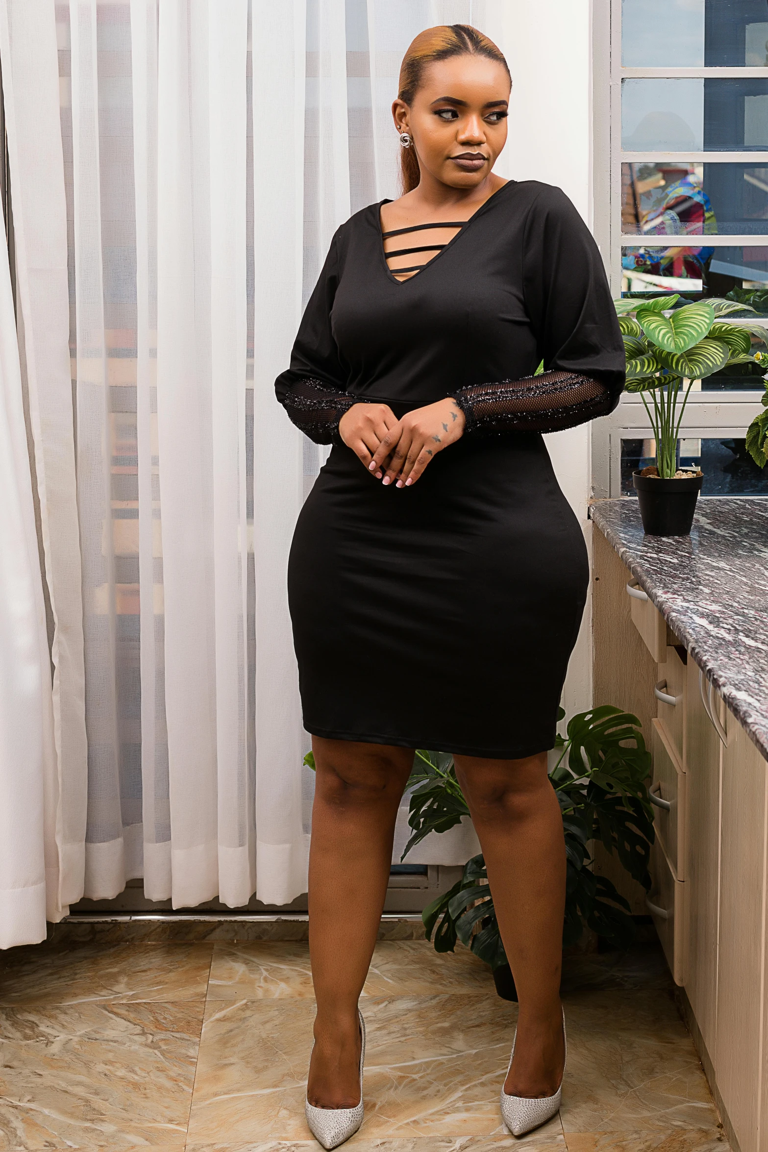 a woman wearing white shoes and a black dress in a kitchen