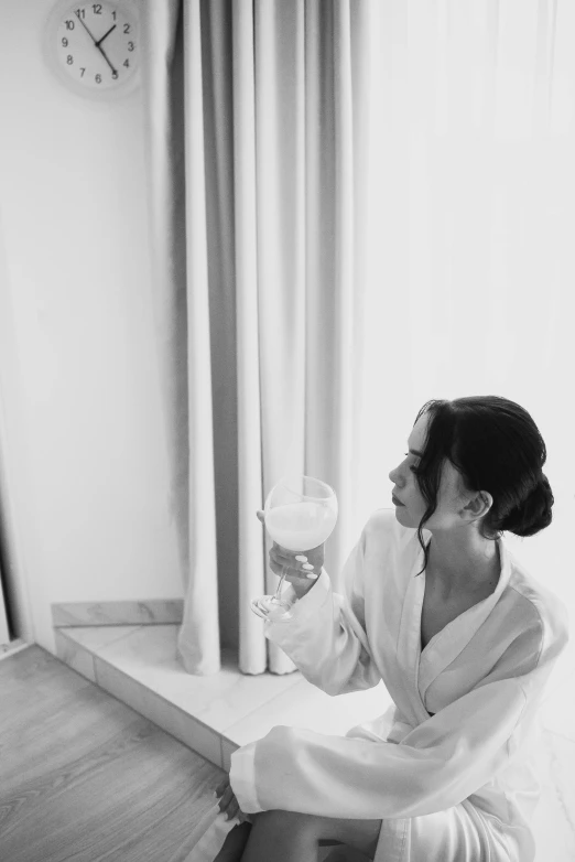 a lady sits on the floor holding a beverage