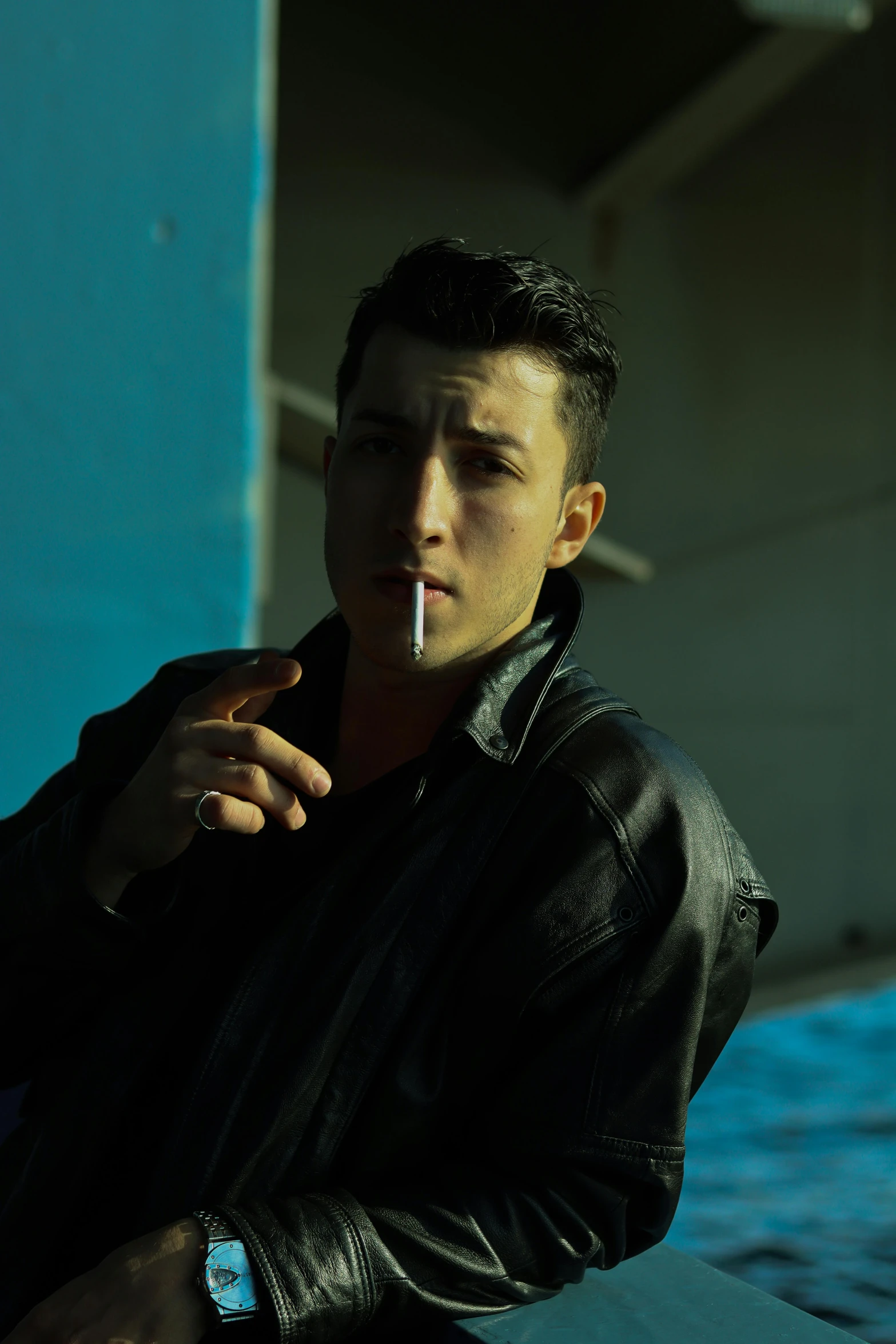 a man in black jacket smoking and looking down