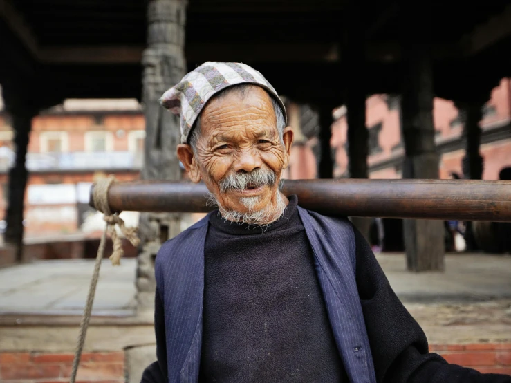 an old man is carrying a large object on his back