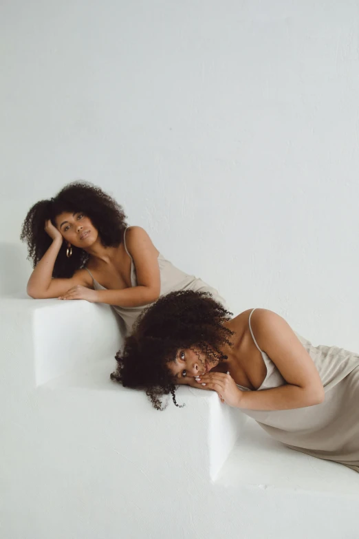 two women are sitting on a set of white blocks and posing for a po