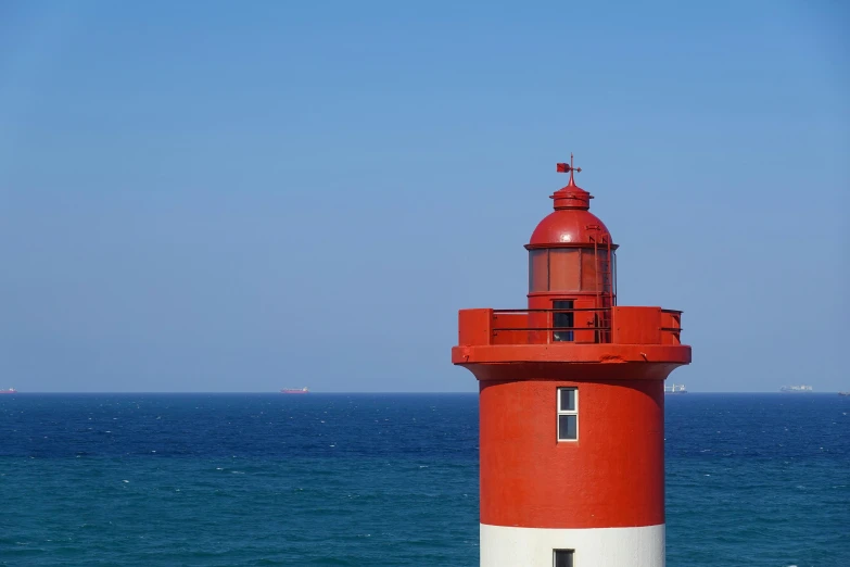 a red and white lighthouse on the shore