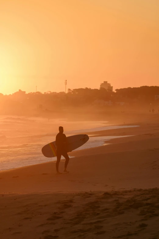 a surfer holding his surfboard while standing on the beach