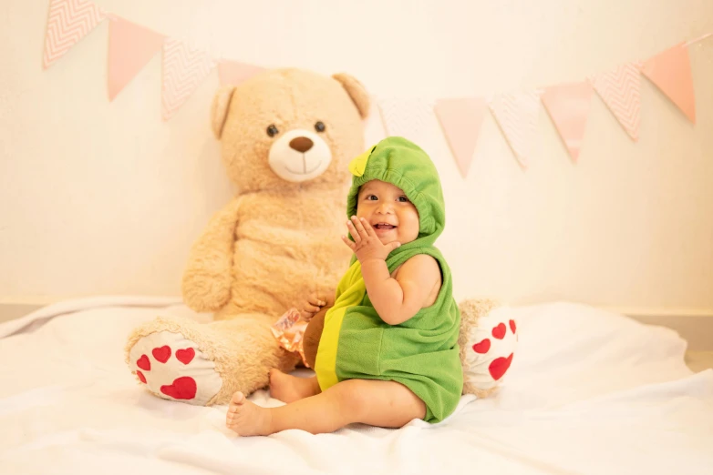 a smiling baby sitting in front of a teddy bear