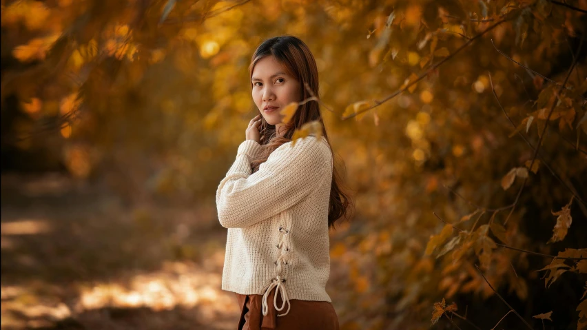 woman in sweater and brown skirt in forest in autumn