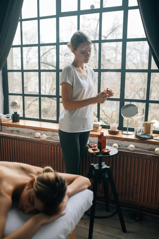 a woman in white shirt laying on bed in front of window