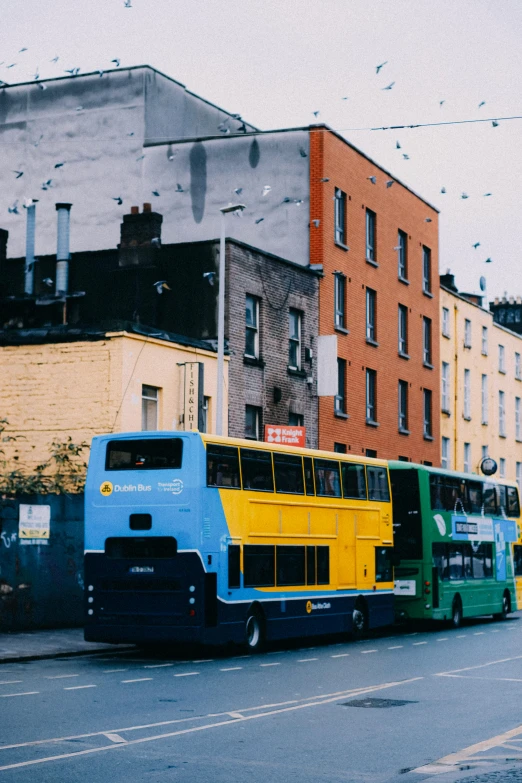 a line of passenger buses parked along side of a building