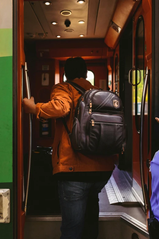 a woman wearing a backpack walks into the elevator of a train