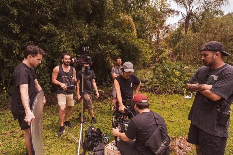 a group of men standing around a field next to a forest