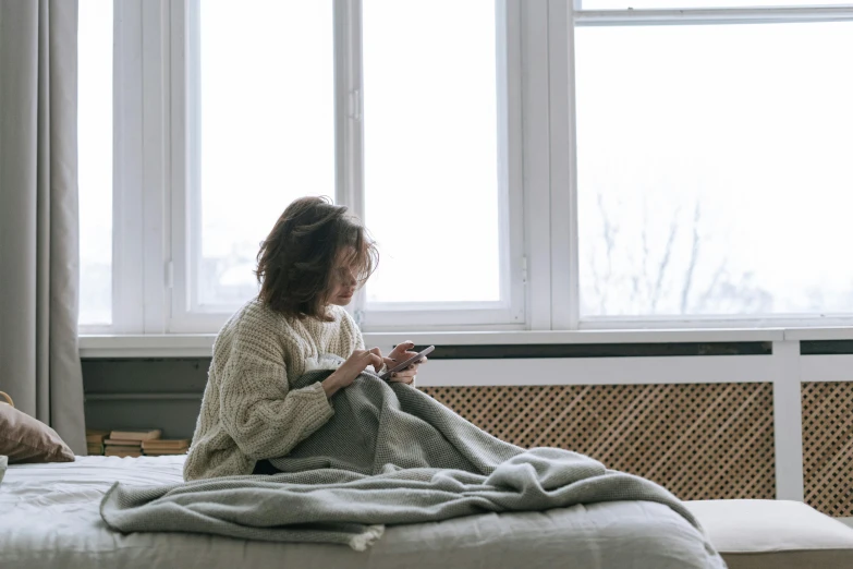 the young woman is using her cellphone on the bed