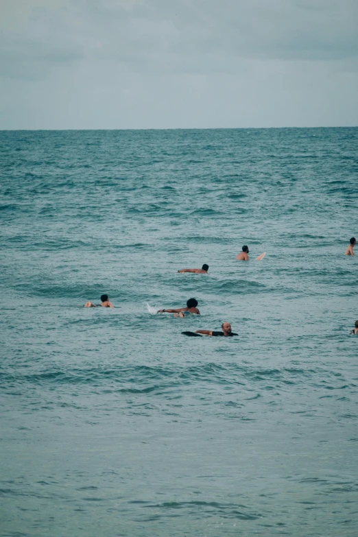 several people swimming in the ocean on surfboards