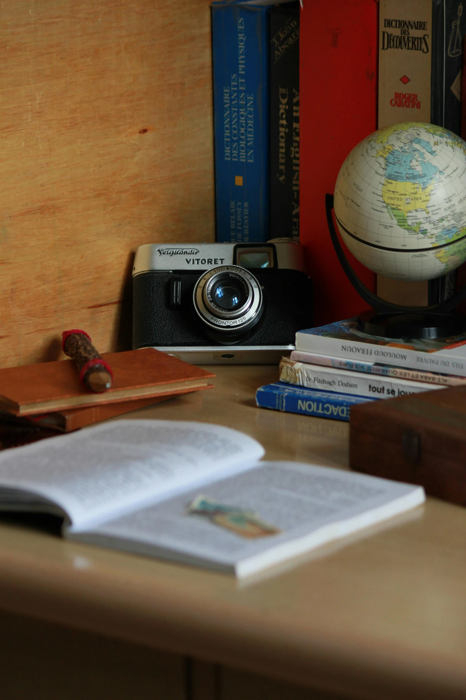 a globe, books, camera and other assorted items sit atop a desk