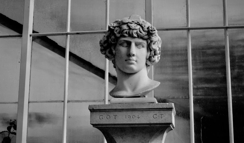 a bust sitting up against a fence in front of a building