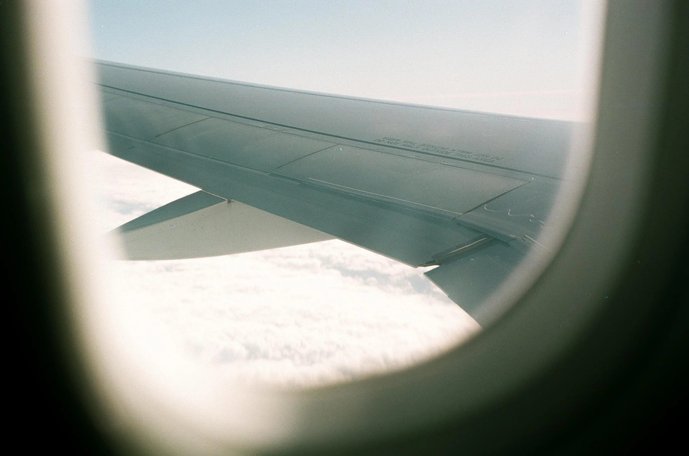 the view through an airplane window shows a wing and clouds