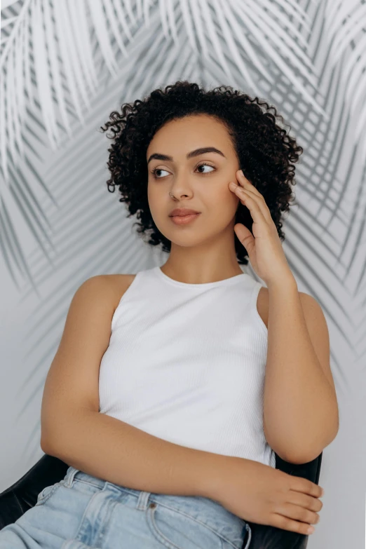 woman in a white tank top with her arms resting on her head