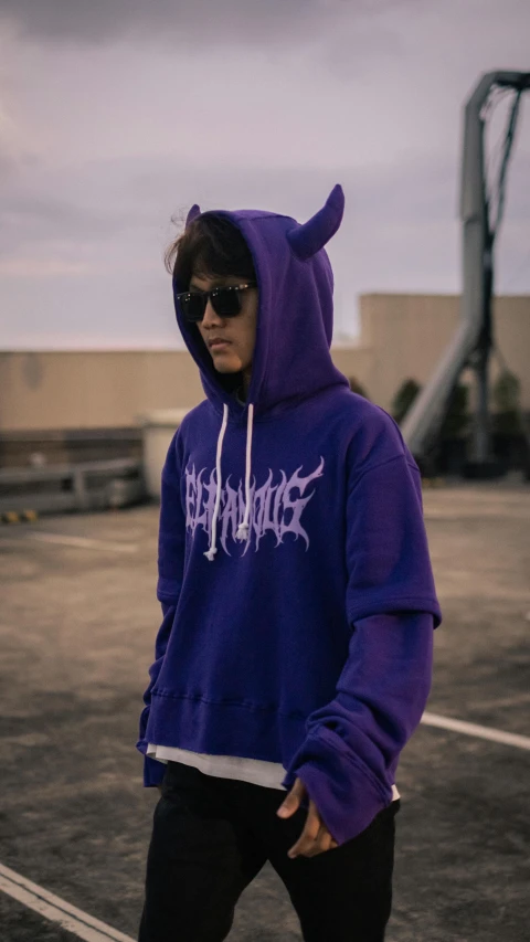 a man with a purple hoodie is in a parking lot