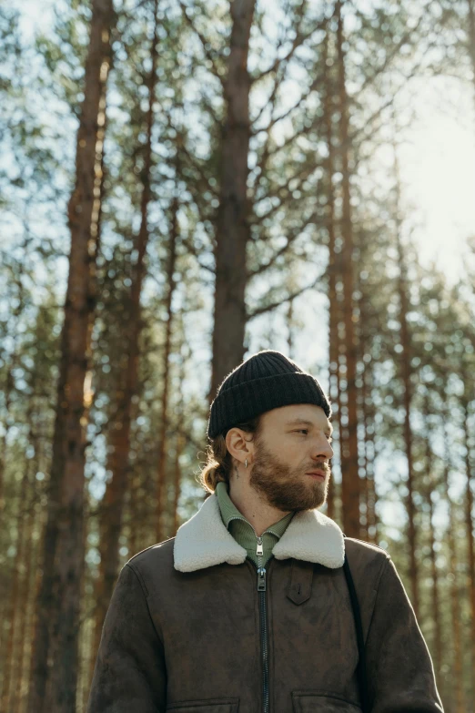 bearded man in winter attire standing in the woods