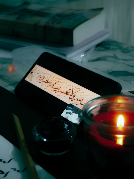 an electronic device with calligraphy sitting next to a glass of water