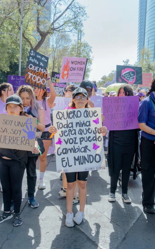 a group of people standing on top of a sidewalk holding signs