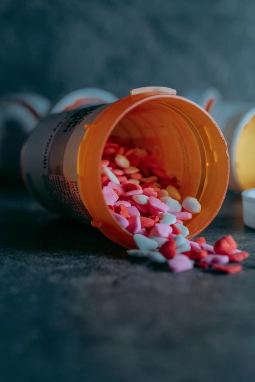 a red and white pill bottle with pills spilling out