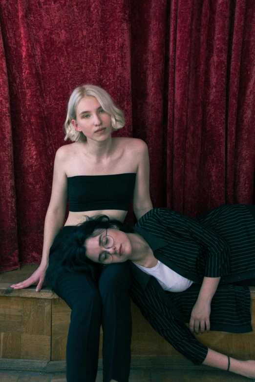 a pair of women sitting on the ground posing for a po