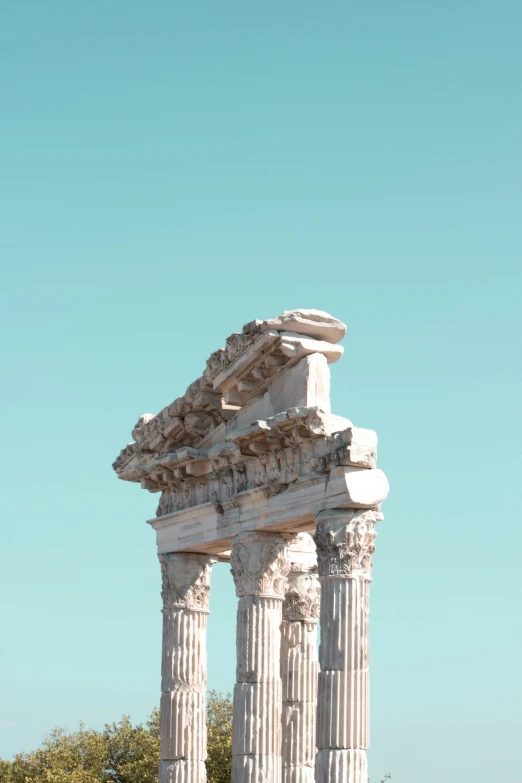 a tall white column with two pillars with statues around it