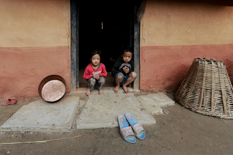 two children sit in the doorway of a home