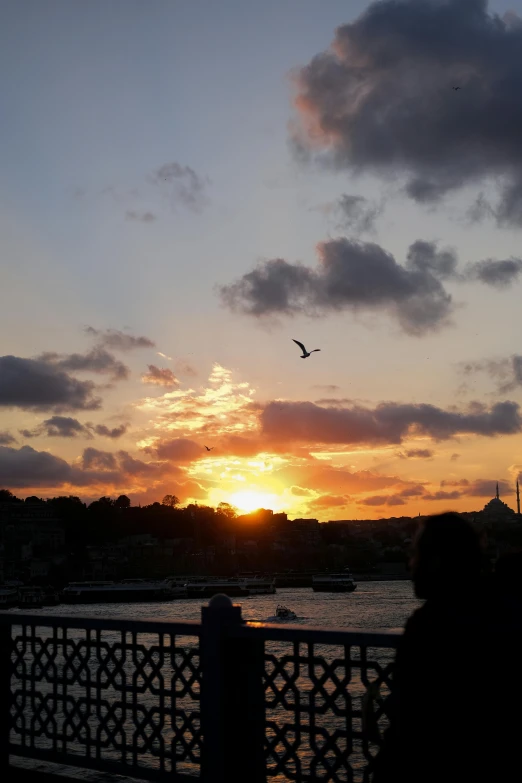 the sun sets over a pier in front of a city