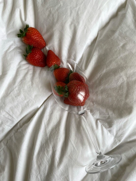 a couple of strawberries sitting next to a wine glass