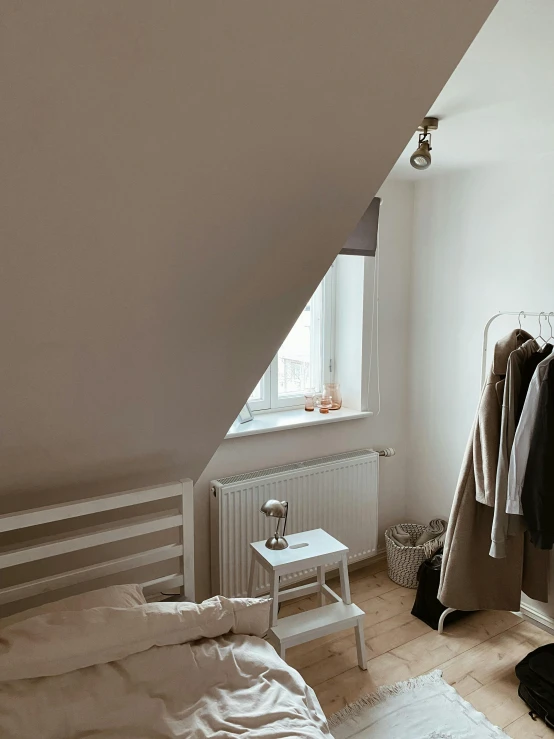 a bedroom that has some clothes hanging on the wall